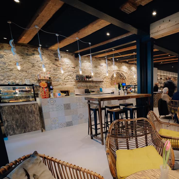 Innenraum des Café Siebzehn 82 mit Natursteinwand, Holzbalken und gemütlicher Sitzecke.