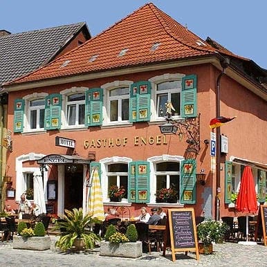 Gasthof Engel in Endingen mit grünen Fensterläden, Außenbestuhlung und Sonnenschirmen.