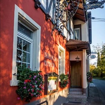 Roter Eingangsbereich des Gasthauses Limburg mit Blumenschmuck und Fachwerk.