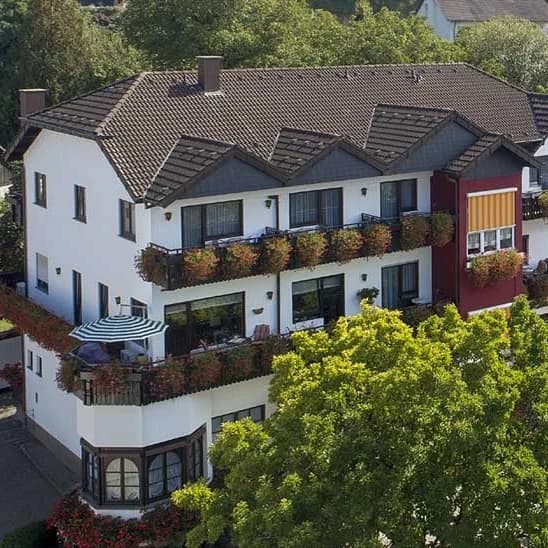 Hotel Riegeler Hof aus der Vogelperspektive, umgeben von Bäumen und mit blumengeschmückten Balkonen.