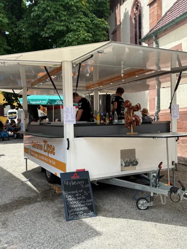 Ein Verkaufsstand mit Tischen, wo Getränke und Snacks angeboten werden.